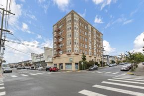 San Francisco apartment for rent - A street view of a city with a tall building in the middle.