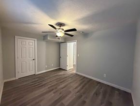 East Point apartment for rent - A room with a ceiling fan and light fixture, two doors, and a wooden floor.