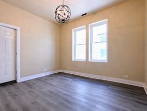 Chicago apartment for rent - an empty living room with a white door and two windows