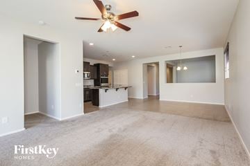 Surprise house for rent - A spacious living room with a ceiling fan and a kitchen in the background.