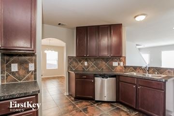 Humble house for rent - A kitchen with brown cabinets and a marble counter top.