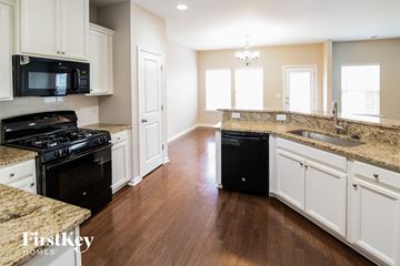 Summerville house for rent - A kitchen with a black stove top oven and a black trash can.