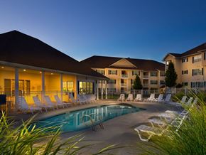 Andover apartment for rent - A pool surrounded by lounge chairs in front of a building.