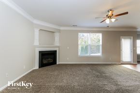 Gastonia house for rent - A spacious living room with a fireplace and a ceiling fan.