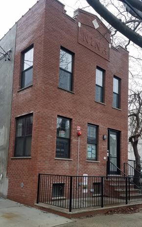 Brooklyn apartment for rent - A red brick building with a black iron fence in front.