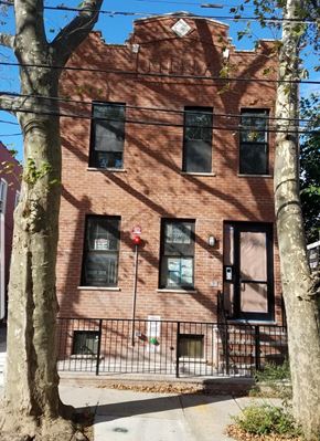 Brooklyn apartment for rent - A red brick building with a black gate in front.