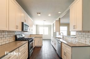 Baytown house for rent - a kitchen with white cabinets and a stove and a sink