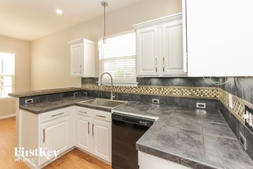 Mooresville house for rent - a kitchen with marble counter tops and white cabinets