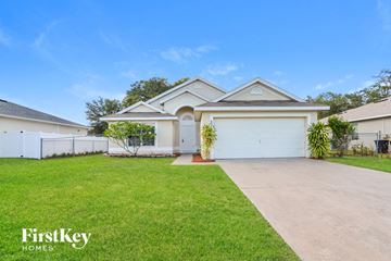 Poinciana house for rent - a white house with a driveway and a lawn