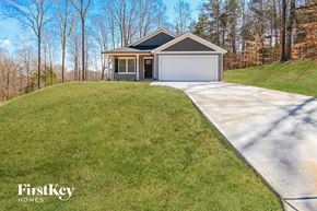 Kannapolis house for rent - A house with a garage is situated on a grassy hill.