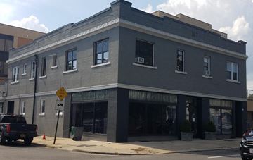 Mineola apartment for rent - A grey building with a yellow sign in front of it.