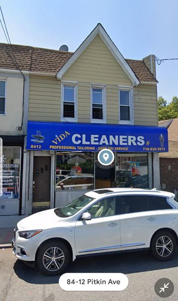 Ozone Park apartment for rent - A white car is parked in front of a building with a blue sign that reads "Vida Cleaners".