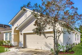 Jacksonville house for rent - A house with a white garage door and a tree with red leaves in front of it.