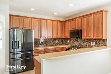 Jacksonville house for rent - A kitchen with wooden cabinets and a black fridge.