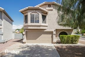 Chandler house for rent - a side view of a beige house with a garage and a tree