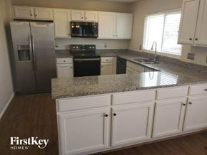 Amelia house for rent - a kitchen with white cabinets and granite counter tops