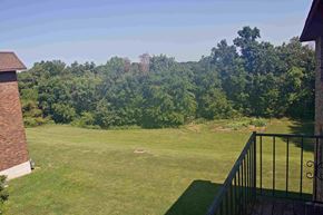 Jefferson City apartment for rent - A view from a balcony overlooking a lush green lawn and trees.