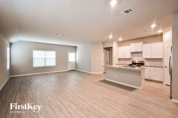 San Antonio house for rent - an open kitchen and living room with wood flooring and white cabinets