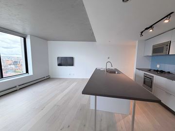 Vancouver apartment for rent - A modern kitchen with a grey countertop and white cabinets.