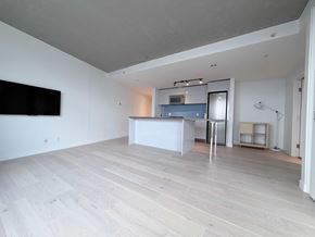 Vancouver apartment for rent - A spacious room with a television on the wall and a bar area.