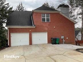 Mableton house for rent - a driveway in front of a brick house with two garage doors