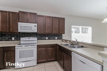 Sorrento house for rent - a kitchen with brown cabinets and white appliances and a sink