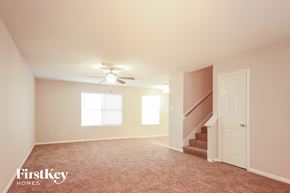 Humble house for rent - a living room with carpeted stairs and a ceiling fan