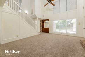 Spring house for rent - a large carpeted living room with a staircase and a ceiling fan