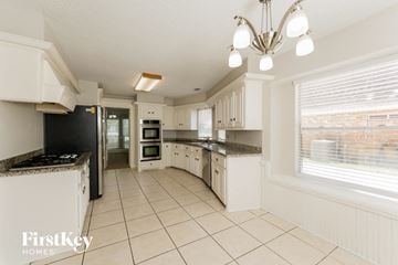 Spring house for rent - a large kitchen with white cabinets and tiled floors