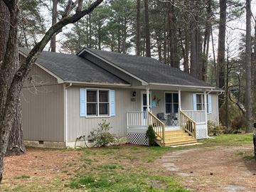 Lusby house for rent - A small house with a porch and a tree in front of it.