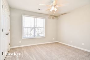 Greensboro house for rent - a bedroom with carpet and a ceiling fan and a window