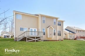 Greensboro house for rent - a yellow house with a deck and a grassy yard