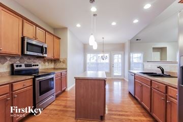 Indian Trail house for rent - A kitchen with wooden cabinets and a FirstKey Homes logo.