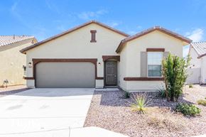 Buckeye house for rent - a beige house with a garage door and a driveway