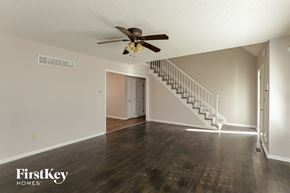Kansas City house for rent - an empty living room with a ceiling fan and a staircase
