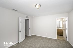 Jacksonville house for rent - a bedroom with white walls and carpet and a door to a bathroom