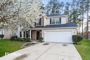 Kannapolis house for rent - A two-story house with a garage is surrounded by trees and has a white flowering tree in the front yard.