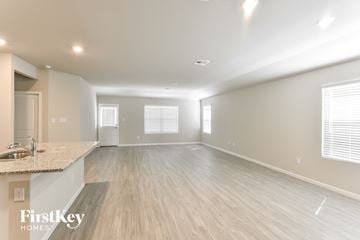 San Antonio house for rent - A spacious room with wooden flooring and a kitchen area with a sink.