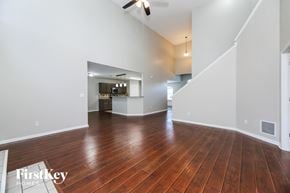 Middleburg house for rent - A spacious room with wooden floors and a staircase leading to another room.