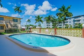 Hollywood apartment for rent - a swimming pool in front of a building with palm trees