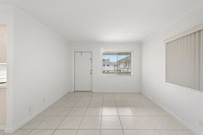 Hollywood apartment for rent - the living room and dining room of a house with white walls and tiled floors