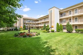 Evergreen Park apartment for rent - the view of an apartment building with a green lawn and a fountain