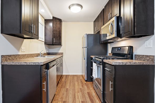 Villa Park apartment for rent - a kitchen with black appliances and wood flooring and black cabinets