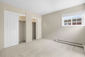 Naperville apartment for rent - A room with a carpeted floor, a window with blinds, and a door leading to another room.