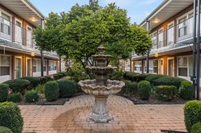 Downers Grove apartment for rent - A fountain in the middle of a courtyard surrounded by bushes and trees.