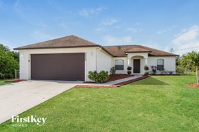 Lehigh Acres house for rent - A white house with a brown roof and a brown garage door.