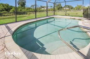 Lehigh Acres house for rent - A small pool with a glass enclosure and a metal fence.