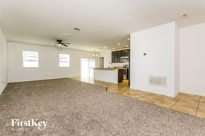 Poinciana house for rent - A spacious empty room with a fan on the ceiling and a carpet on the floor.