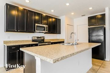 Poinciana house for rent - A kitchen with black cabinets and a granite countertop.
