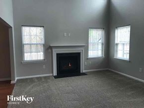 Huntersville house for rent - an empty living room with a fireplace and three windows